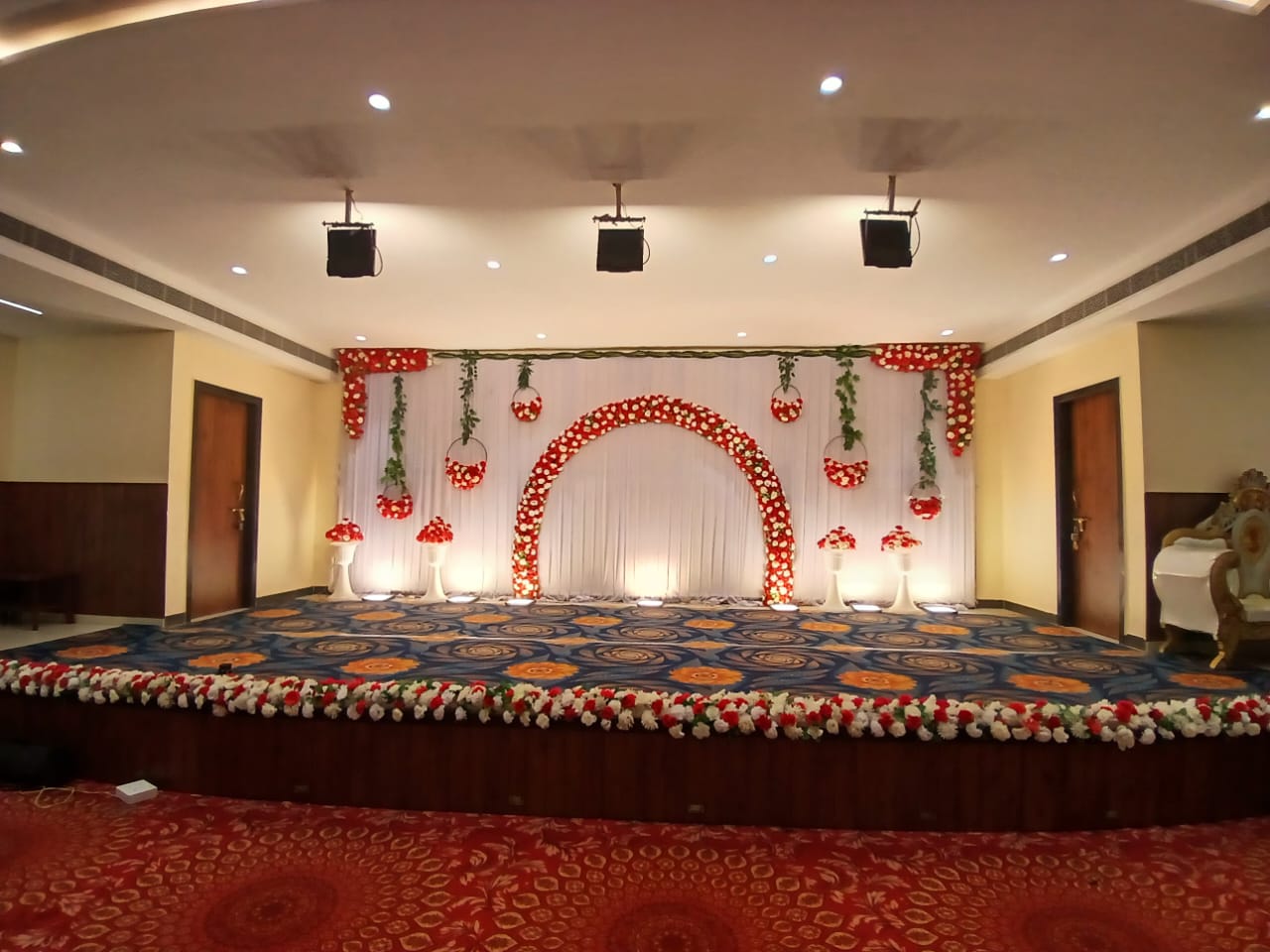 Stage with a red and white floral arch backdrop and floral stage edging